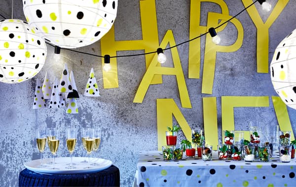 Pièce décorée sur le thème des pois pour le réveillon de Nouvel An, avec nourriture sur une table, boissons dans des verres et décorations lumineuses.