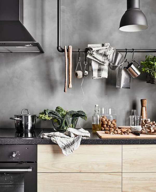 Plan de travail motif granit et tiroirs en imitation frêne, à côté d’une table de cuisson, d’un four et d’une hotte.