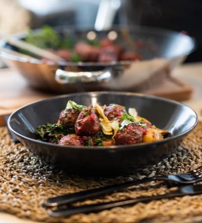 Plant balls with kale and lingonberries placed in dark dish