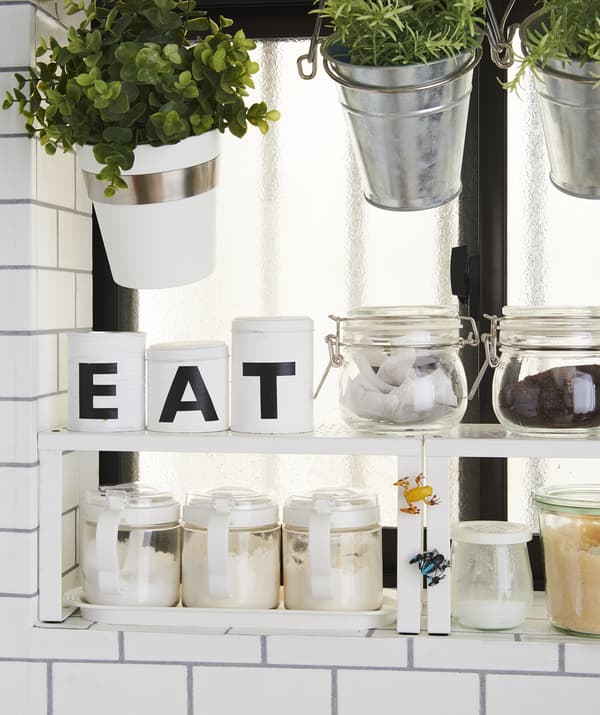 Plants and dry ingredients stored in pots and jars on a shelf insert.