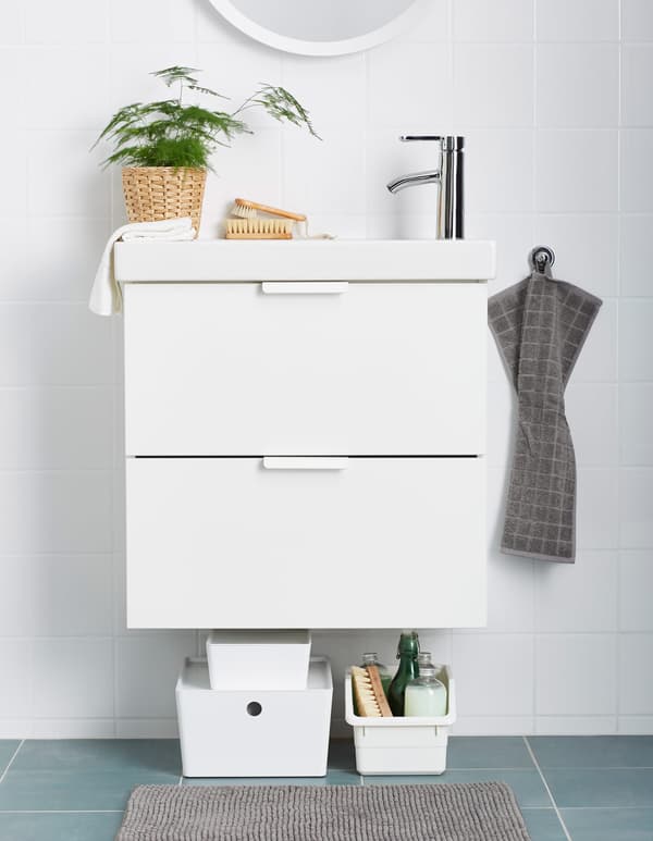 Plastic boxes hold cleaning supplies and sit beneath a bathroom sink.
