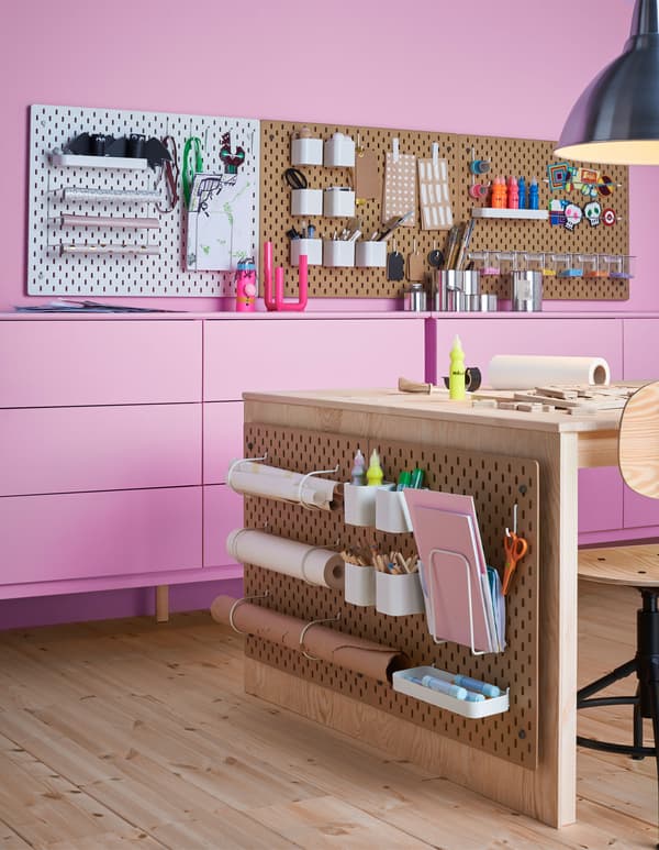 Plusieurs panneaux perforés SK&Aring;DIS dans un coin bricolage, avec accessoires pour les fournitures, le papier et autres. 