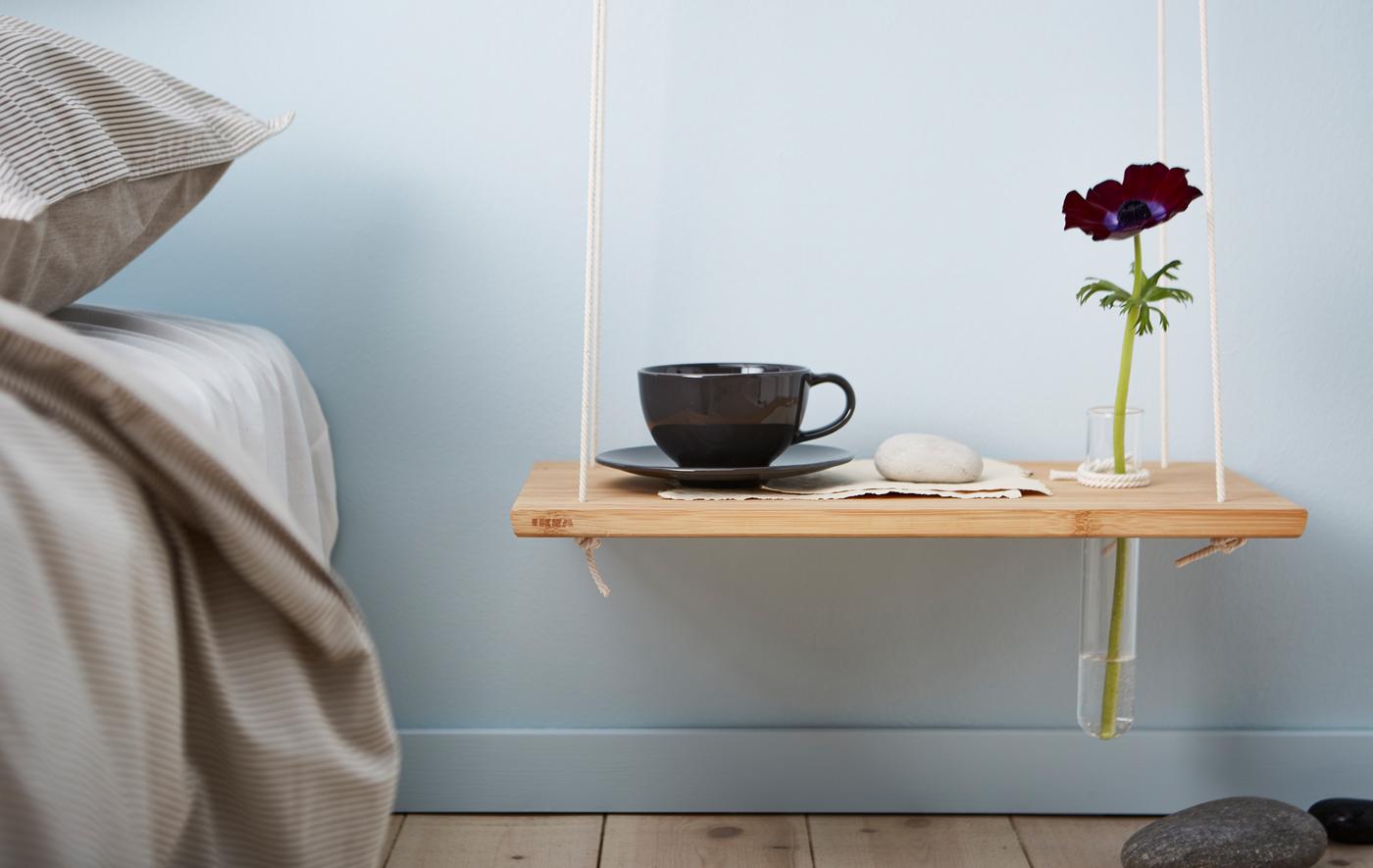 Plusieurs tables de chevet réalisées avec des caissons cubiques au mur, une planche à découper suspendue et une boîte de rangement posée sur des cache-pots