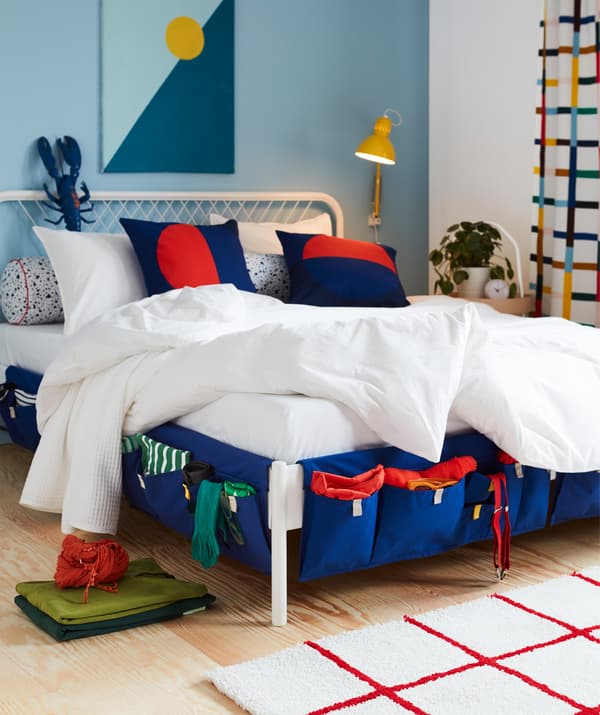 Poches de rangement en tissu bleu MÖJLIGHET, utilisées pour les chaussettes, les bretelles et autres, accrochées sur les côtés d’un lit.