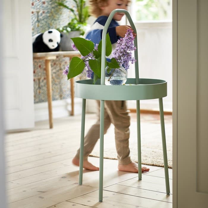 Poiss kõnnib ümber rohelise laua, millel on lilled.