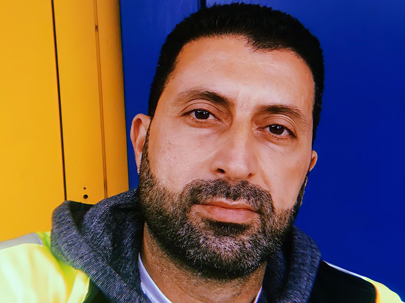 Portrait d'Odai, un réfugié irakien et collaborateur chez IKEA Suisse, sur fond jaune et bleu.