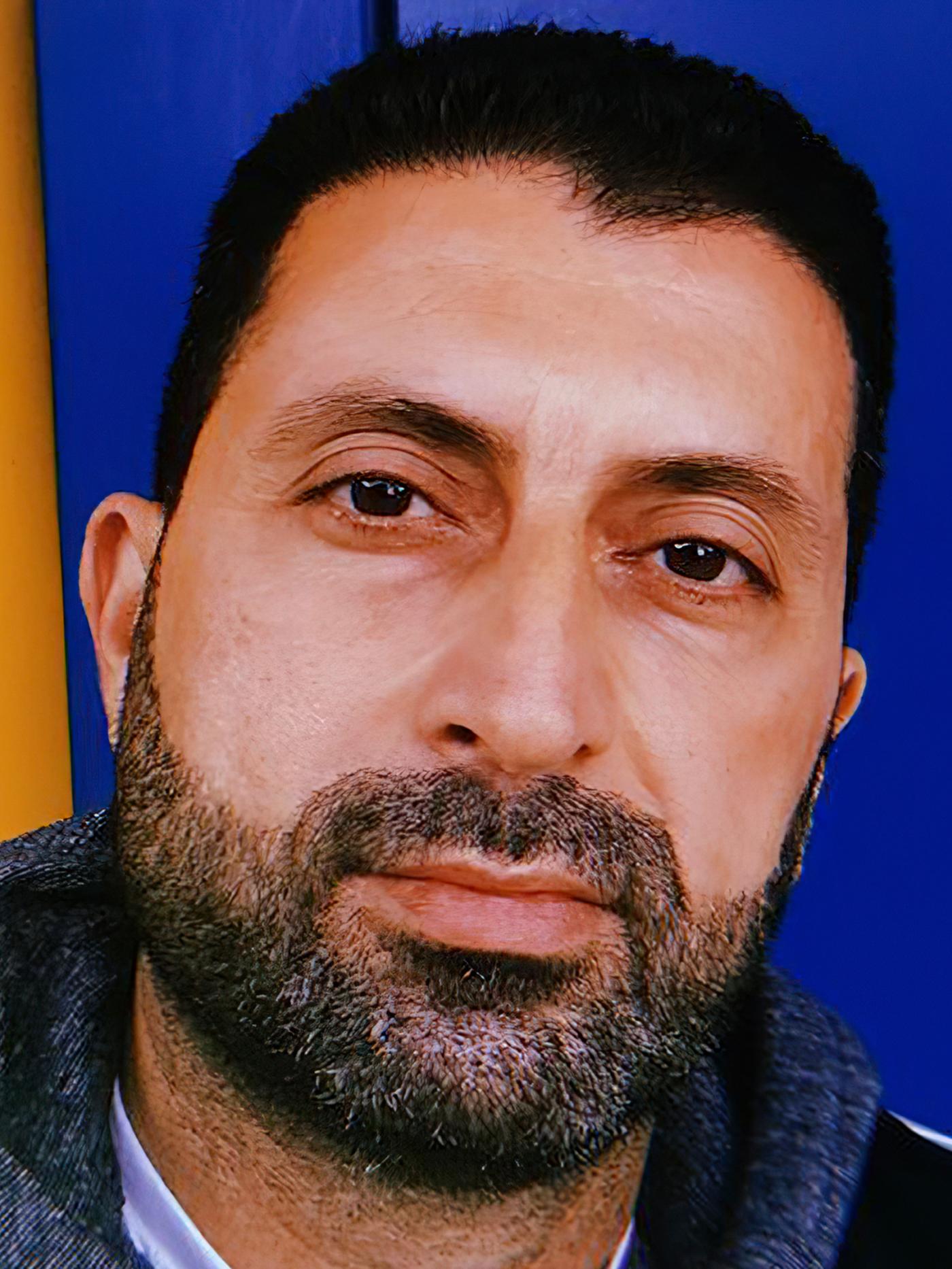 Portret Odaija, iraškega begunca in zaposlenega v podjetju IKEA v Švici, ki se smehlja.