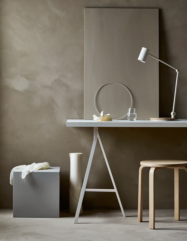 Poste de travail dans un séjour minimaliste, avec bureau, fauteuil et fournitures cachées dans un cube de rangement