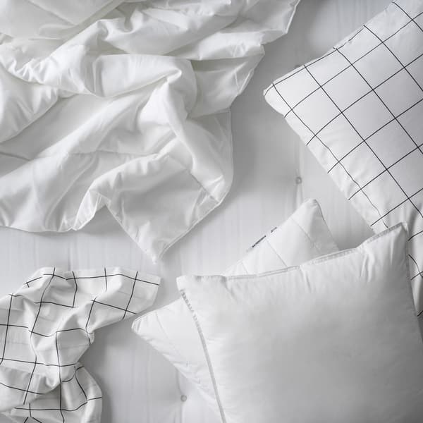 Primer plano de ropas de camas blancas sobre un colchón blanco. Se aprecian sábanas, plumones y almohadas.