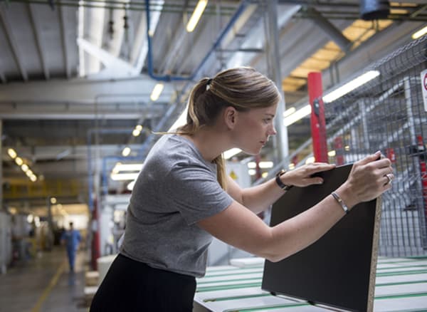 Product developer Anna Granath holding a black kitchen front in a factory.
