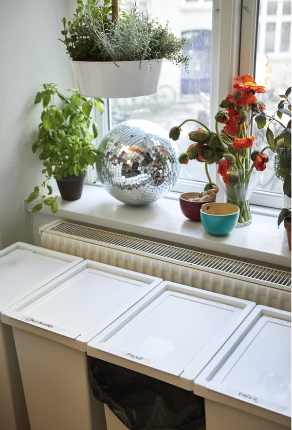 Quatre bacs de tri des déchets sous le rebord de fenêtre, dans la cuisine.