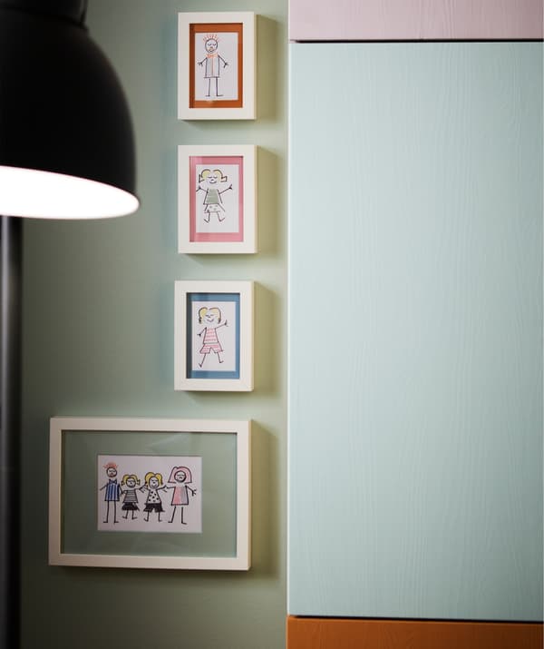 Quatre cadres RIBBA avec illustrations accrochés à un mur, à côté d’éléments muraux IVAR.