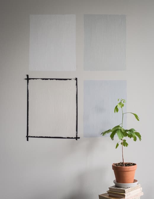 Quatre carrés de couleurs différentes peints sur un mur gris
