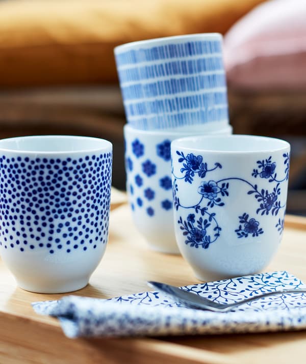 Quatre petites tasses de thé blanches décorées de motifs différents en bleu foncé.