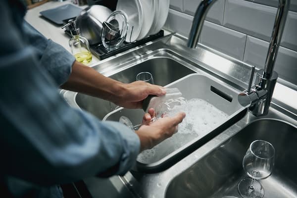 Quelqu'un lave la vaisselle à la main et dans un bac GRUNDVATTNET.