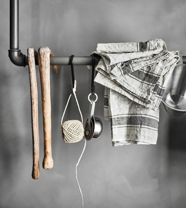 Rail réalisé avec de vieux tuyaux, servant de rangement à des ustensiles de cuisine et à des objets décoratifs.