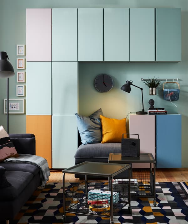 Rangement IVAR multicolore intégré à un salon peint en vert clair et meublé d’un canapé VALLENTUNA gris foncé.