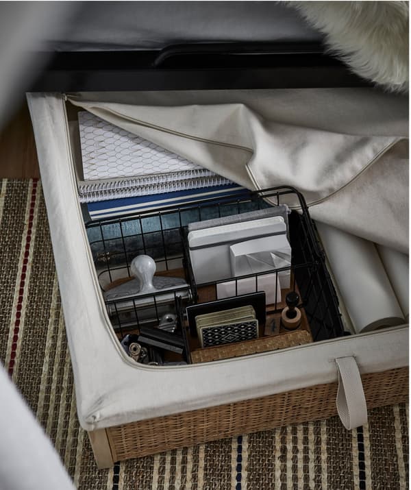 Rangement pour lit IKEA RÖMSKOG placé sous un lit et rempli de matériel d’étude.