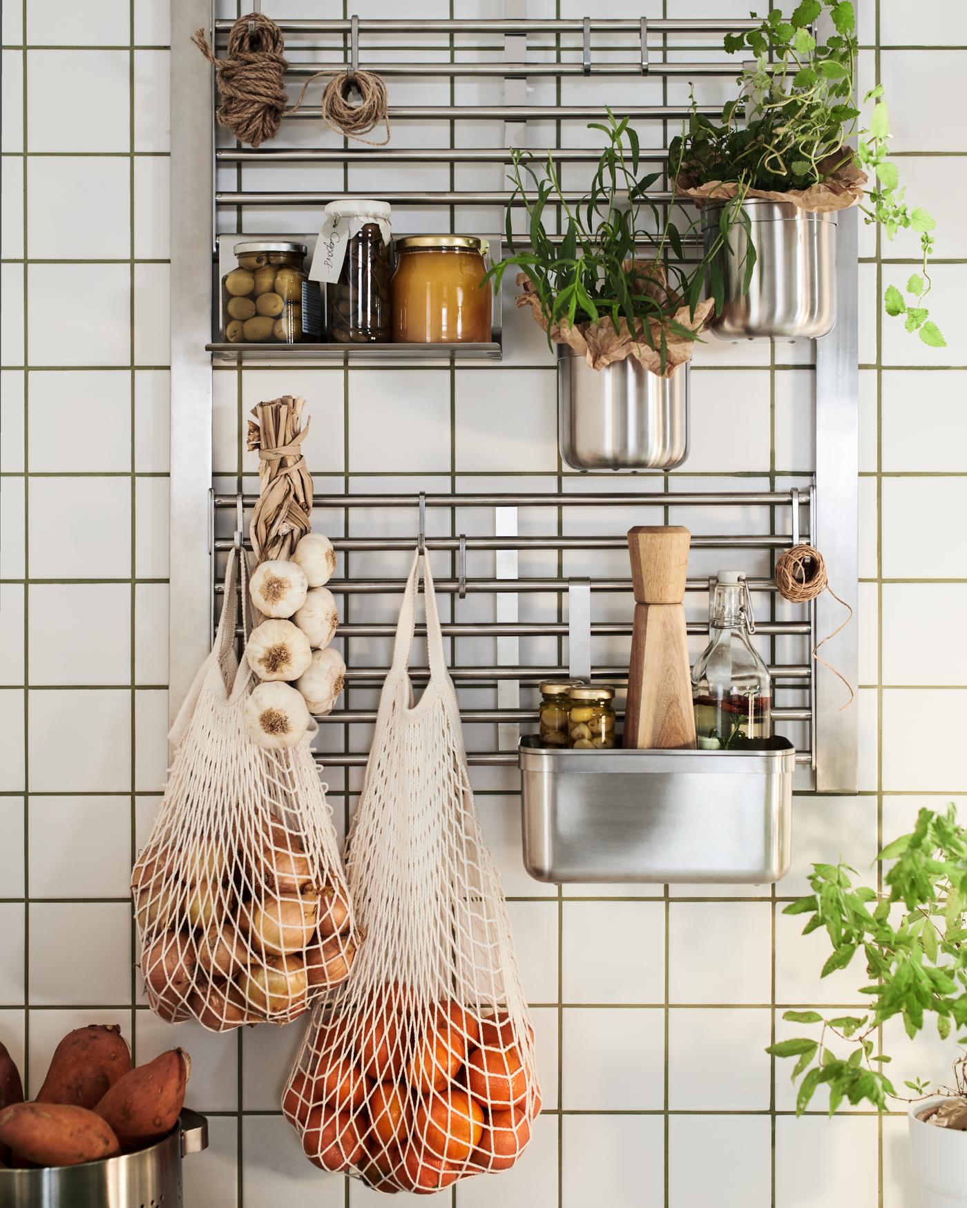 Repisa de metal KUNGSFORS donde se apoyan mallas con verduras y estantes con plantas y artículos de cocina.