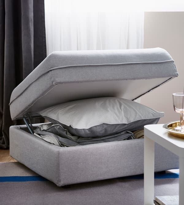 Repose-pieds ouvert, rempli de linge de lit.