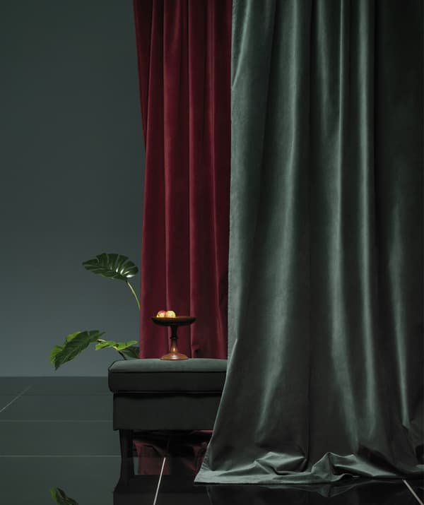Rideaux de velours rouge foncé et verts drapés autour d'un repose-pieds.