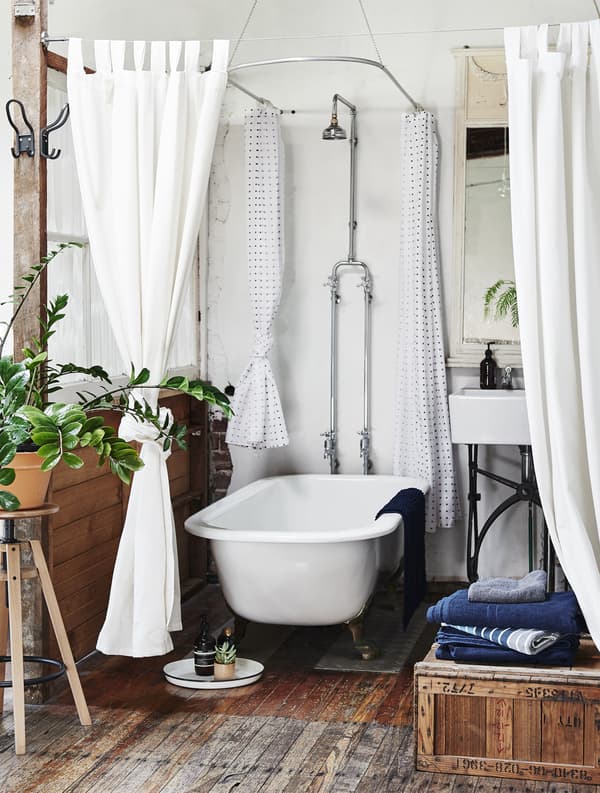 Rideaux et plantes autour d’une baignoire.