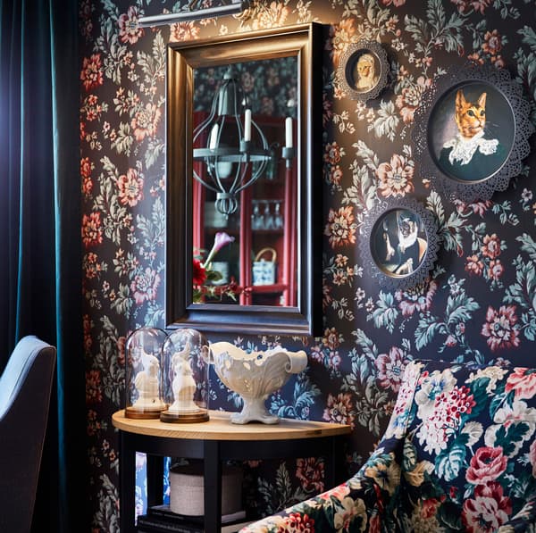Round SKURAR deco plates with cat portraits hanging on a floral wall.