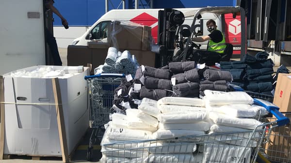  Roušky, přikrývky a další potřebné věci z IKEA ve vozíkách před dodávkou, která je doveze potřebným v nouzi.