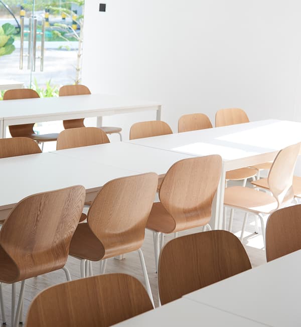 Rows of white tables and wooden chairs.