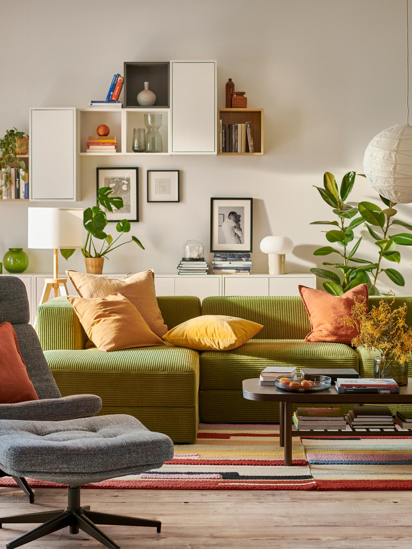 Ruang tamu yang cerah yang berpusat pada sofa dengan chaise longue JÄTTEBO berwarna kuning-hijau gelap dan kabinet lekap dinding EKET.