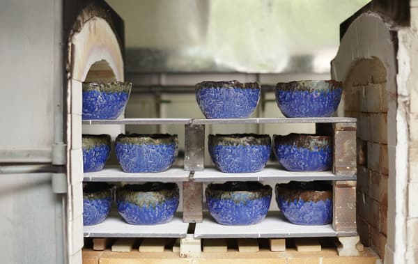 Rustic blue bowls on shelves of a brick kiln.