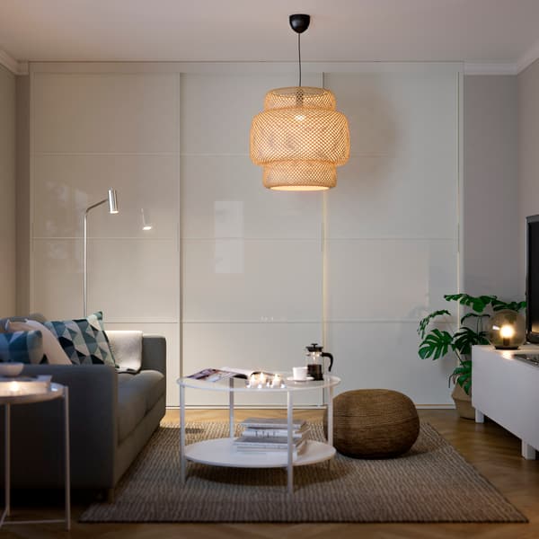 Sala de estar predominantemente clara con un sofá del lado izquierdo, una lámpara colgante y una mesa de centro.