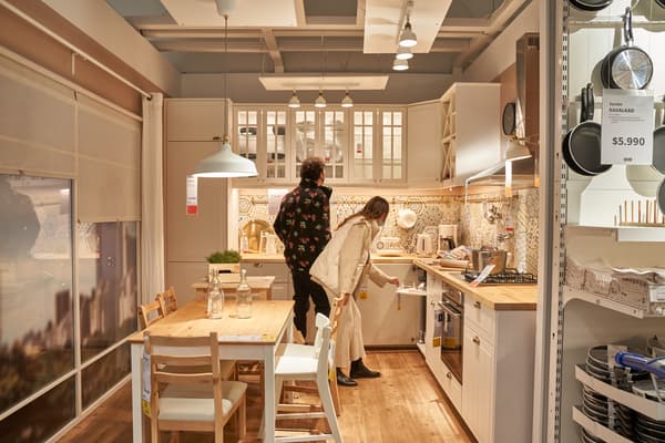 Sala de showroom dentro de la tienda IKEA, donde se pueden tocar, ver y experimentar los muebles que se venden en la tienda. El hombre esta apoyado viendo el celular.