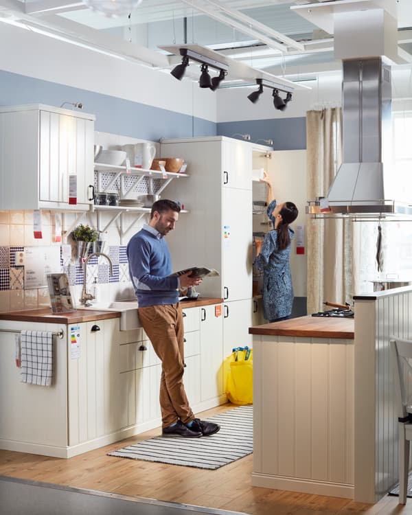 Sala de showroom dentro de la tienda IKEA, donde se pueden tocar, ver y experimentar los muebles que se venden en la tienda. El hombre esta apoyado viendo el celular.