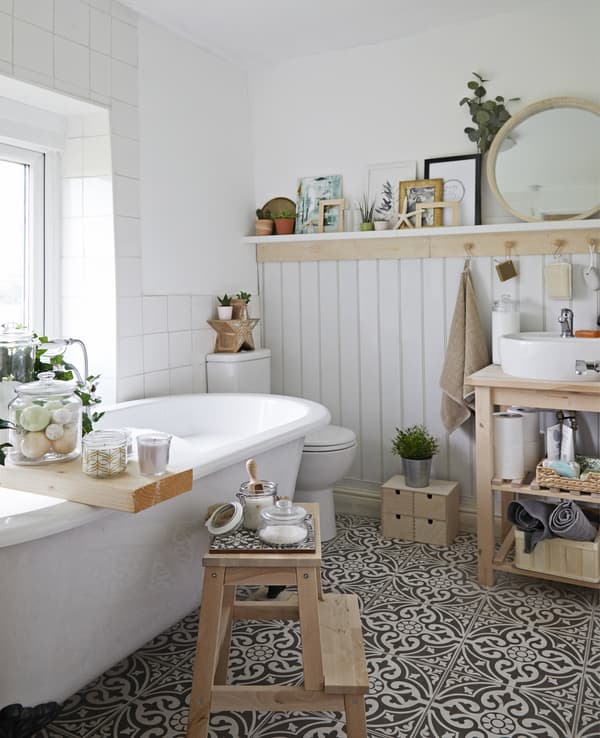 Salle de bains toute blanche, meubles de rangement en bois, pots en verre et sol en carreaux de céramique.