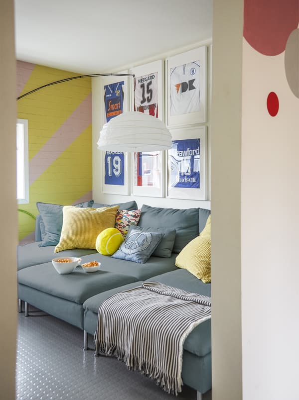 Salle de jeu avec grand canapé et murs colorés.