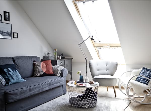 Salon avec canapé gris et deux fauteuils.