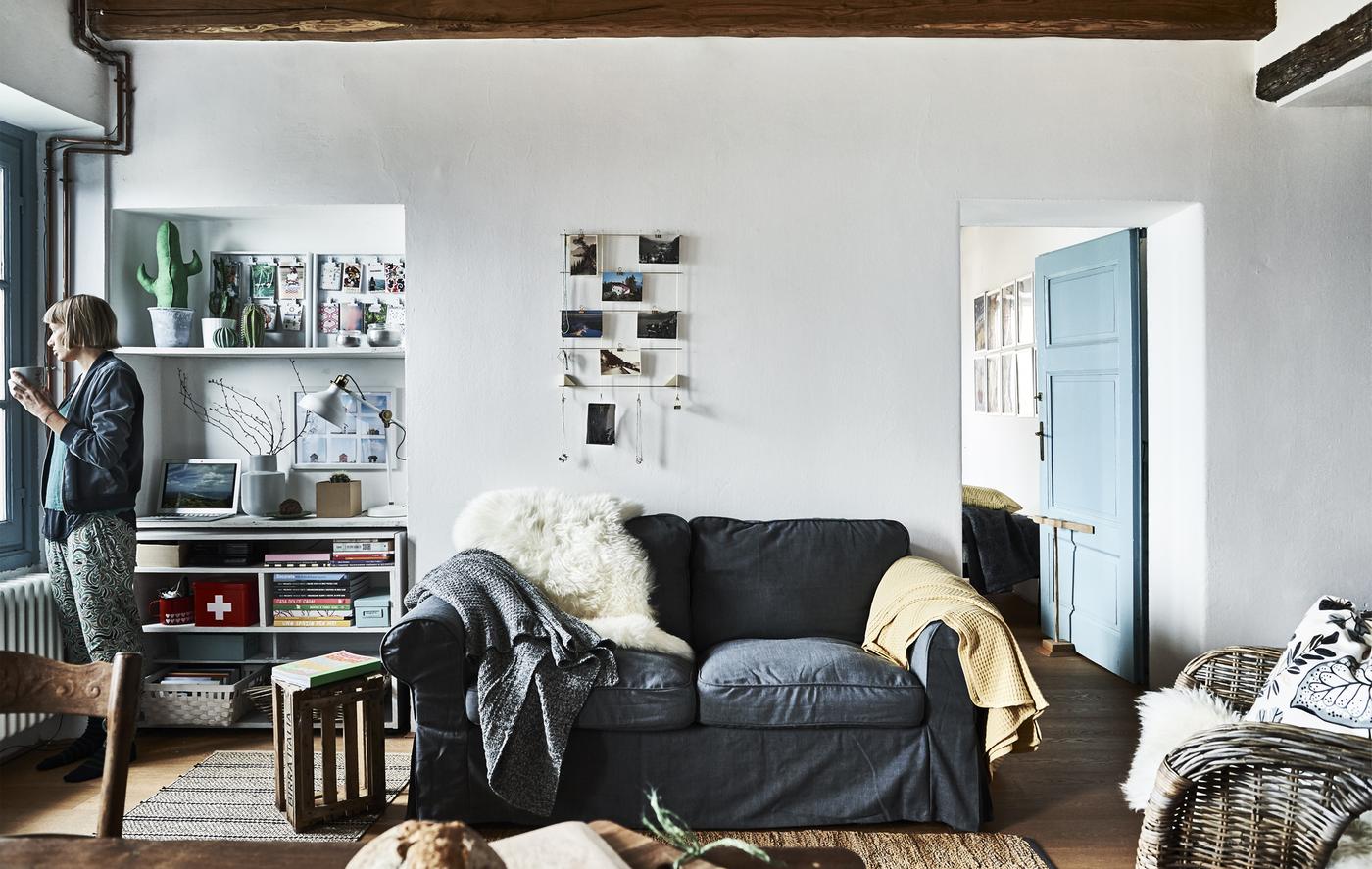 Salon avec murs blancs et canapé gris.