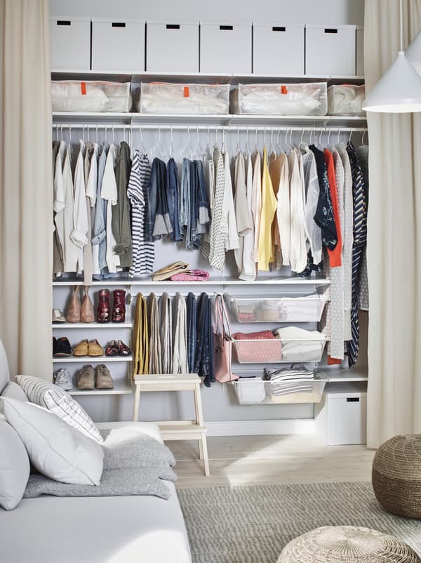 Salon dont un mur est doté de rideaux ouverts pleine hauteur révélant un système de garde-robe couvrant tout le mur.