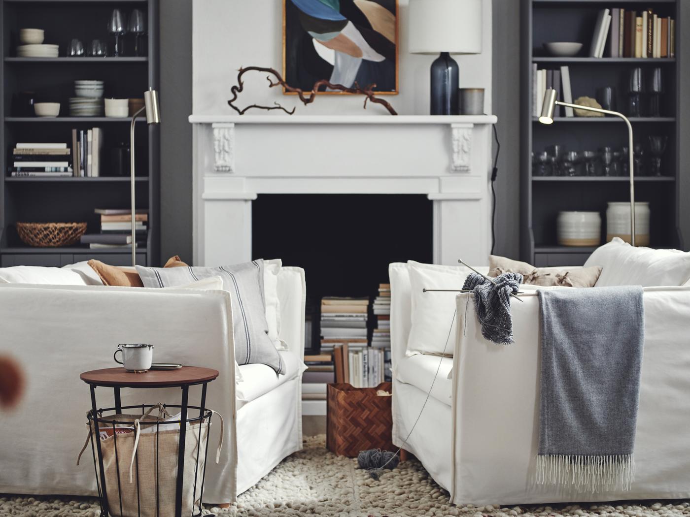 Salon où sont disposés deux fauteuils BACKSÄLEN blancs devant des armoires HAUGA grises encadrant une cheminée.