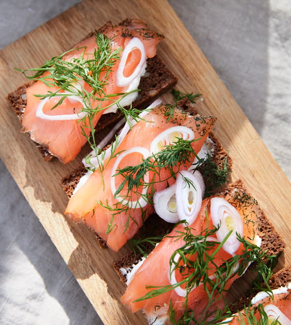 Sandwiches gravlax servis sur une planche à découper en bois.