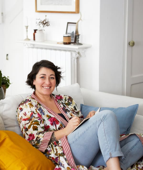 Sarah sitting on a white sofa in a room with white decor.