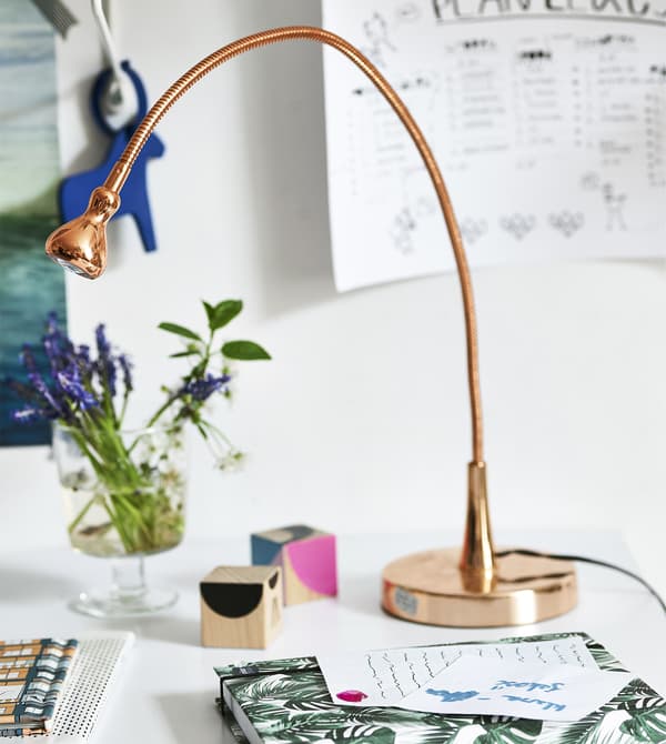 Scrivania arredata con una lampada di rame, fiori e oggetti –IKEA