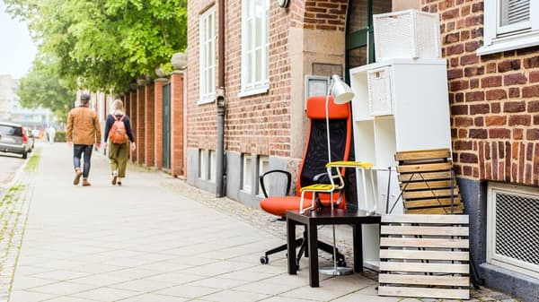 Second-life IKEA furniture stands neatly on the sidewalk in front of a brick building, ready for sustainable reuse.