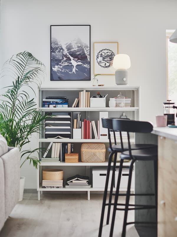 Section of an open floor-plan interior including a kitchen island, a living-room sofa, and a full BEKANT shelving unit.
