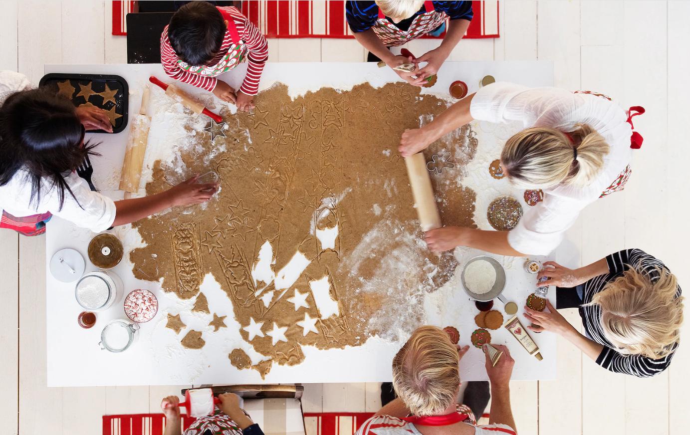 Seis personas alrededor de una mesa rectangular. Unas amasan otras cortan galletas navideñas con implementos de repostería de IKEA.
