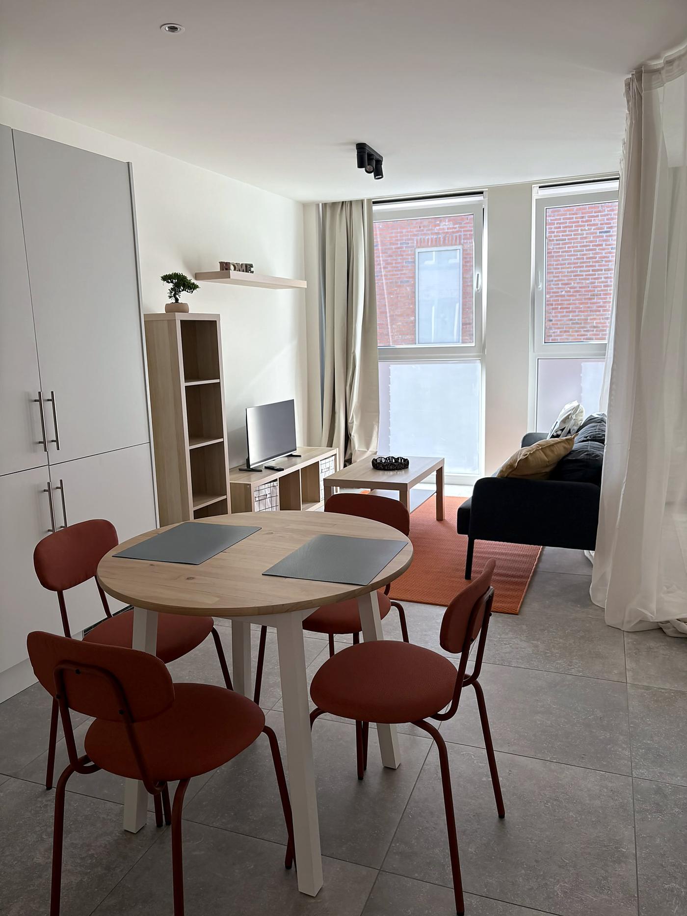 Séjour aménagé du projet Tempo, avec une table, des chaises rouges, un canapé et une fenêtre de toit.
