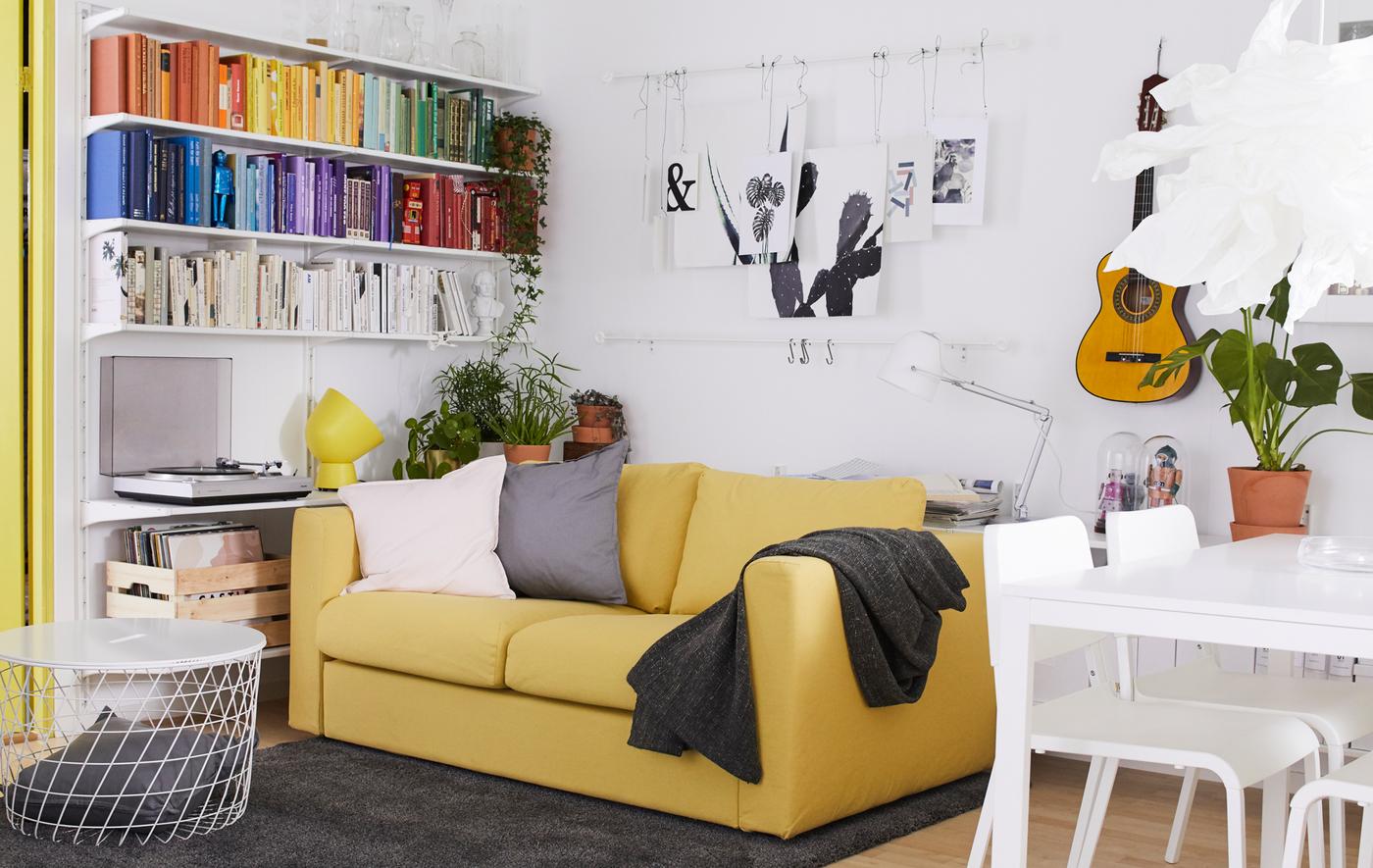 Séjour décoré en blanc et jaune, avec des touches d’accent, des œuvres d’art au mur et une table de salle à manger.