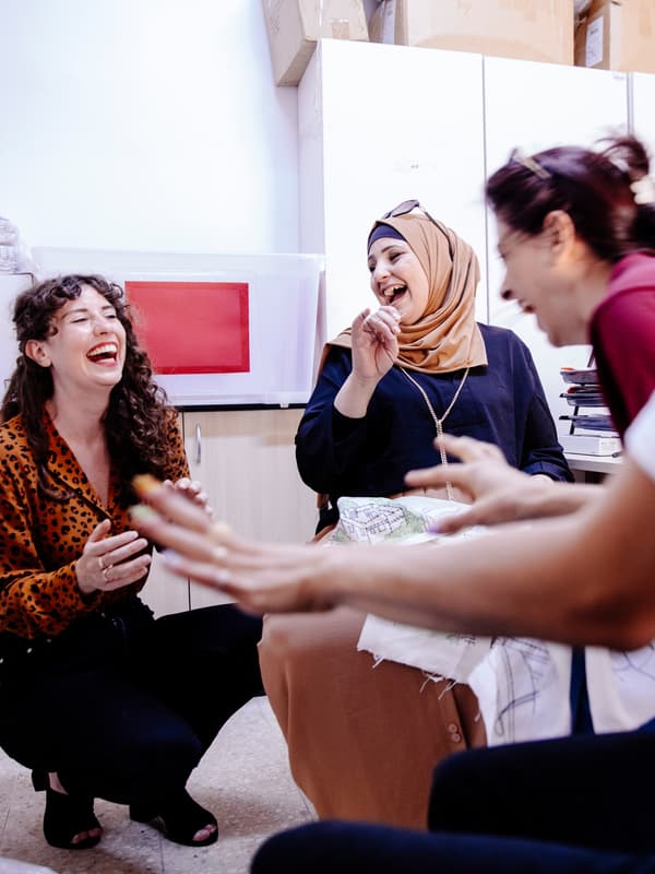 Seorang pekerja IKEA dan beberapa artisan dari Jordan River Foundation ketawa terbahak-bahak di bengkel pereka bentuk.