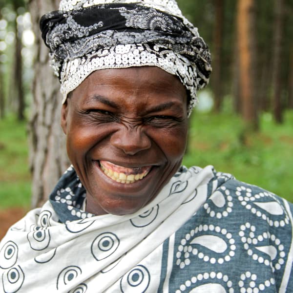 Seorang wanita Uganda, tersenyum lebar, yang terlibat dalam projek White Nile.